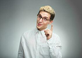 Young man in glasses with a funny expression on his face and thumbs up photo