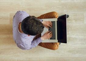 Top view of man sitting on the floor and working with a laptop photo