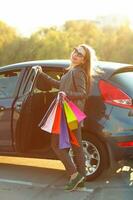 sonriente caucásico mujer poniendo su compras pantalones dentro el coche foto