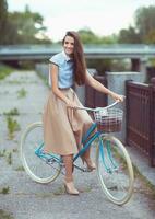 joven mujer hermosa, elegantemente vestida con bicicleta foto