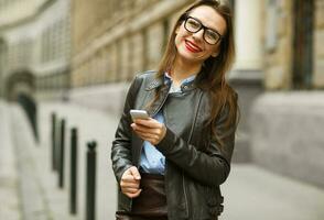 mujer de negocios caminando abajo el calle mientras hablando en inteligente teléfono foto