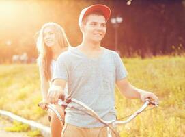 Happy couple riding a bicycle in the park outdoors photo