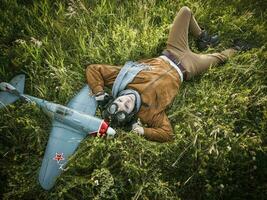 joven chico en Clásico ropa piloto con un avión modelo al aire libre foto