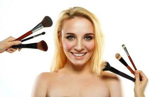sonriente joven mujer con maquillaje cepillos cerca su cara foto