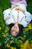 Young smiling girl in Ukrainian costume with a wreath on his head in a meadow photo