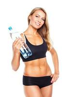 Young athletic girl with bottle of water on white photo