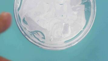 Aloe vera fresco en rodajas y gel líquido en un recipiente de plástico sobre fondo blanco. video
