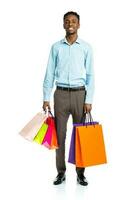 Happy african american man holding shopping bags on white background photo