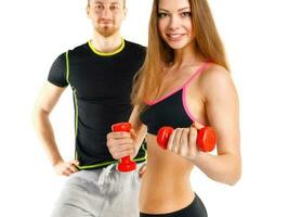 Sport couple - man and woman with dumbbells on the white photo