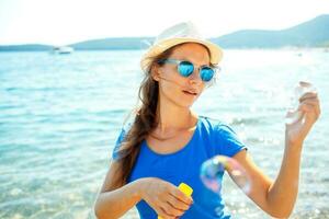 Happy young girl blowing soap bubbles on the seashore photo