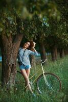 Lovely young woman in a hat with a bicycle in a park photo