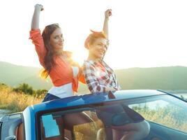 dos joven muchachas teniendo divertido en el cabriolé al aire libre foto