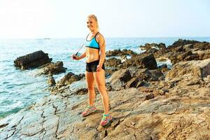 Athlete woman doing sport exercising with the rope on the rocks by the sea photo