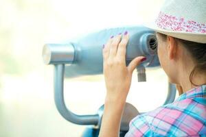 Girl looking through a telescope at the panorama of the city photo