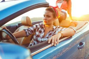 Two young happy girls driving a cabriolet photo