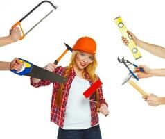 Cheerful girl builder and his hands around her with building tools in them on a white photo