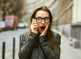 Surprised businesswoman walking down the street while talking on smartphone photo