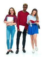 contento estudiantes en pie y sonriente con libros, ordenador portátil y pantalones aislado en blanco foto