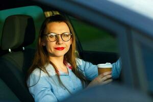 joven mujer con café a Vamos conducción su coche foto