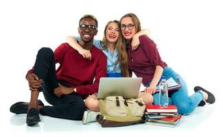 Three students sitting with books, laptop and bags isolated on white background photo