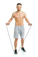 Athletic attractive man jumping on a rope on the white photo