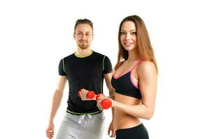 Athletic man and woman with dumbbells on the white photo
