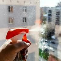 hand sprays washing liquid on window glass closeup photo