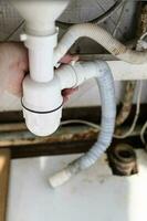 plumber disassembles old siphon with drain hose photo