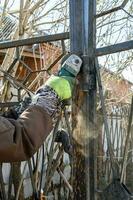 worker cutting hinge on gate of fence in village photo