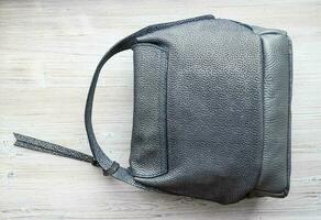 handcrafted grey leather handbag on gray table photo
