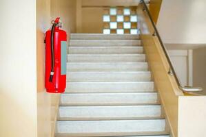 A fire extinguisher hangs up the stairs. Fire safety concept. photo