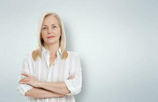 Attractive middle aged woman with folded arms on grey background photo