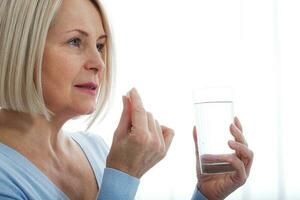 medicine, health care and people concept, close up of middle aged woman taking in pill photo