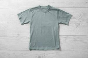 Front views on boys t-shirts on white wooden desk background. Mockup for design closeup photo