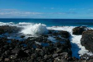 grande olas estrellarse en contra el rocas en el Oceano foto