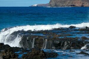 grande olas estrellarse en contra el rocas en el Oceano foto