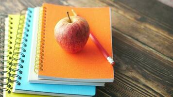 stack of notebook, apple and pencils on table video