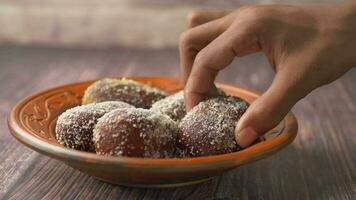 hand pick indian sweet in a bowl on table. video