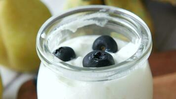 Cerca de yogur fresco con bayas azules en un recipiente video