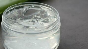 Aloe vera fresco en rodajas y gel líquido en un recipiente de plástico sobre fondo blanco. video