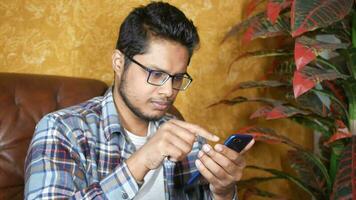 Thoughtful young man hand using smart phone while sit on a sofa video