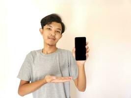 asiático joven hombre demostración teléfono inteligente con blanco pantalla foto