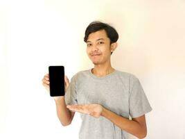 Asian young man showing smartphone with blank screen photo