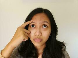 asiático mujer preocupado acerca de acné en su frente aislado en blanco foto