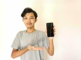 Asian young man showing smartphone with blank screen photo