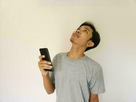 sorpresa cara asiático hombre utilizar teléfono inteligente y frente a arriba con Copiar espacio de anuncio foto