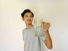 asiático hombre es Bebiendo un vaso de agua y contento foto