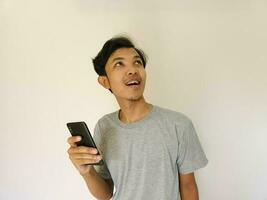 Surprise face asian man use smartphone and facing up with copy space of advertisement photo