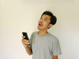 Surprise face asian man use smartphone and facing up with copy space of advertisement photo