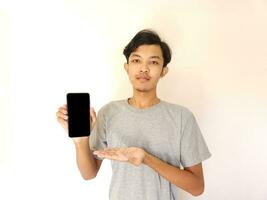 asiático joven hombre demostración teléfono inteligente con blanco pantalla foto